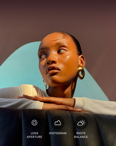 A person with their head turned to the side, bright light shines on them from opposite direction, their hands overlapped on a flat surface in front of them at shoulder height, three photo controls: Lens Aperture, Histogram, and White Balance